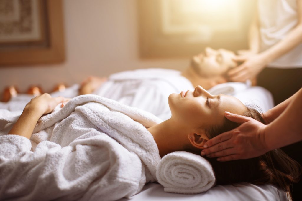 Happy young couple enjoying head massage at the spa